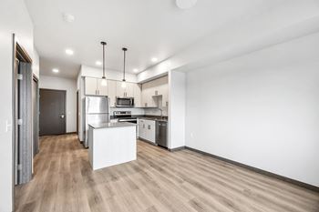 an open kitchen and living room with white walls and wood flooring
